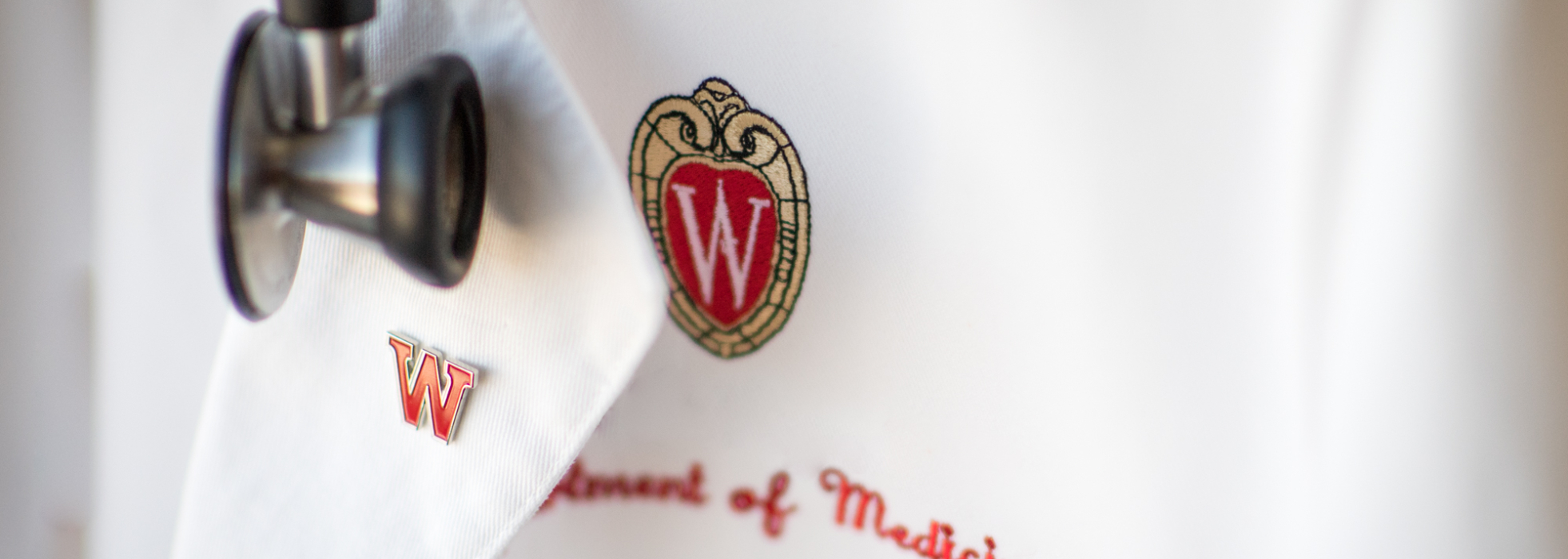 Closeup of white lab coat with Department of Medicine logo and stethoscope