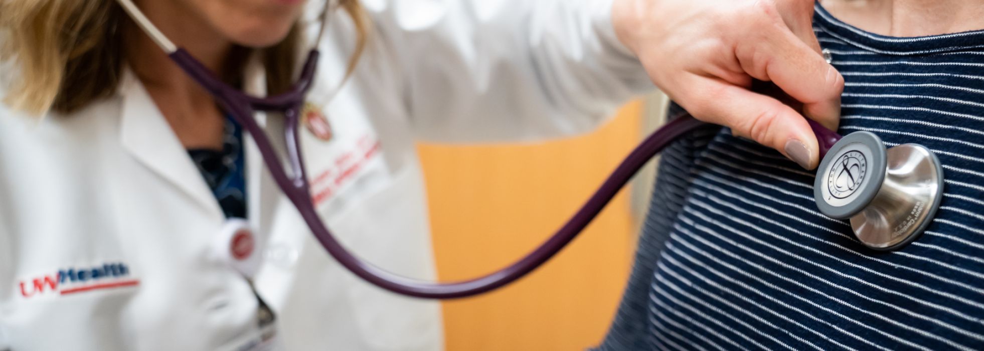 Photo of primary care physician using stethoscope to listen to heartbeat of a patient.
