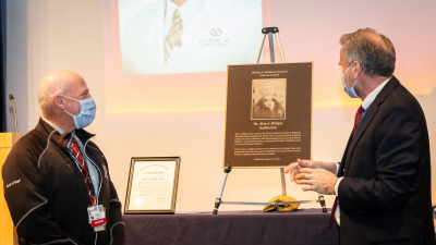 Dr. Alan Bridges, on left, facing Madison VA director John Rohrer, MPH, at the unveiling of the commemorative plaque that will hang outside the newly-named Alan J. Bridges Auditorium at the Madison VA..