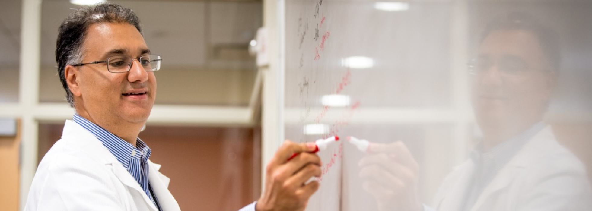 Dr. Sameer Mathur teaching and writing on a whiteboard