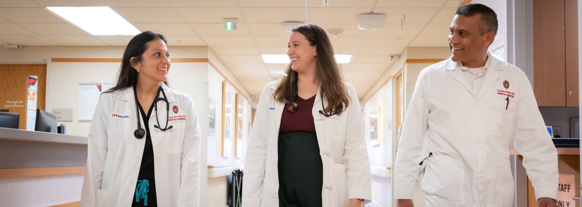 Three doctors in white coats walking down a hospital hallway