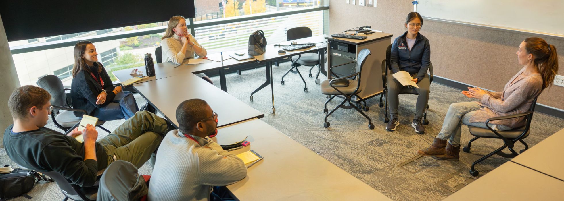 People sitting in a conference room watching a simulated conversation with participants