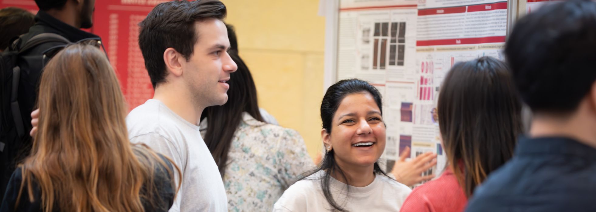 People stand smiling and talking around research posters