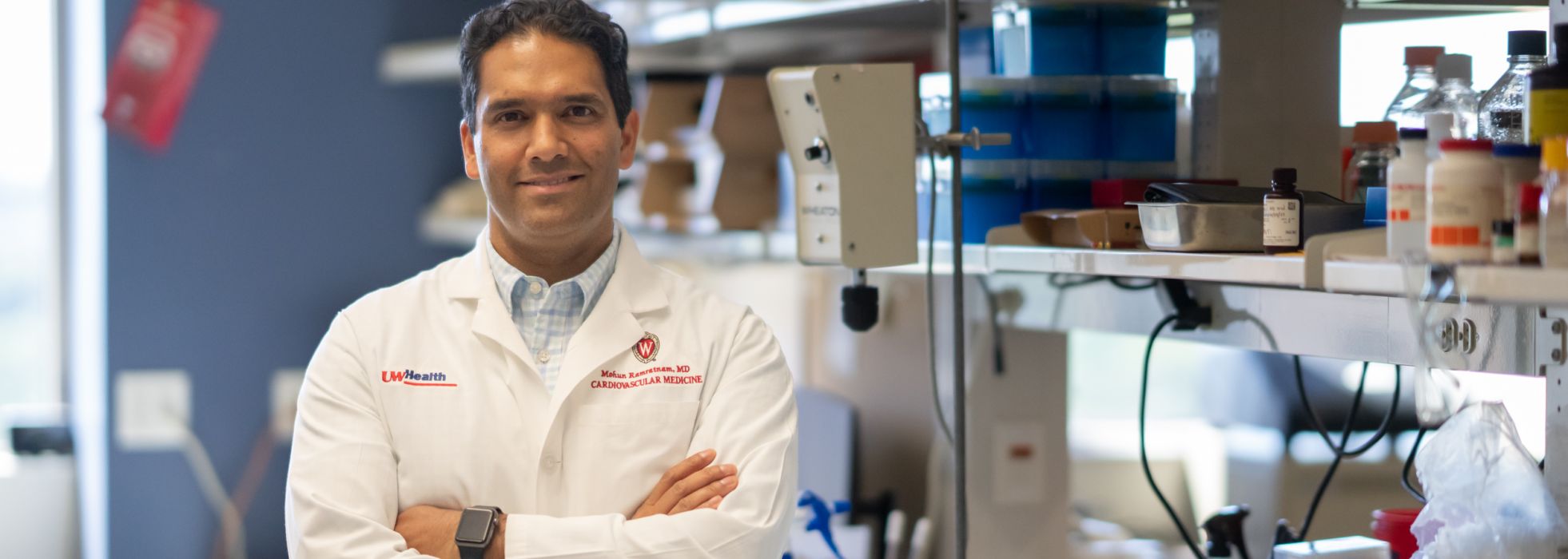 photo of Dr. Mohan Ramratnam wearing white coat and with arms crossed in his lab