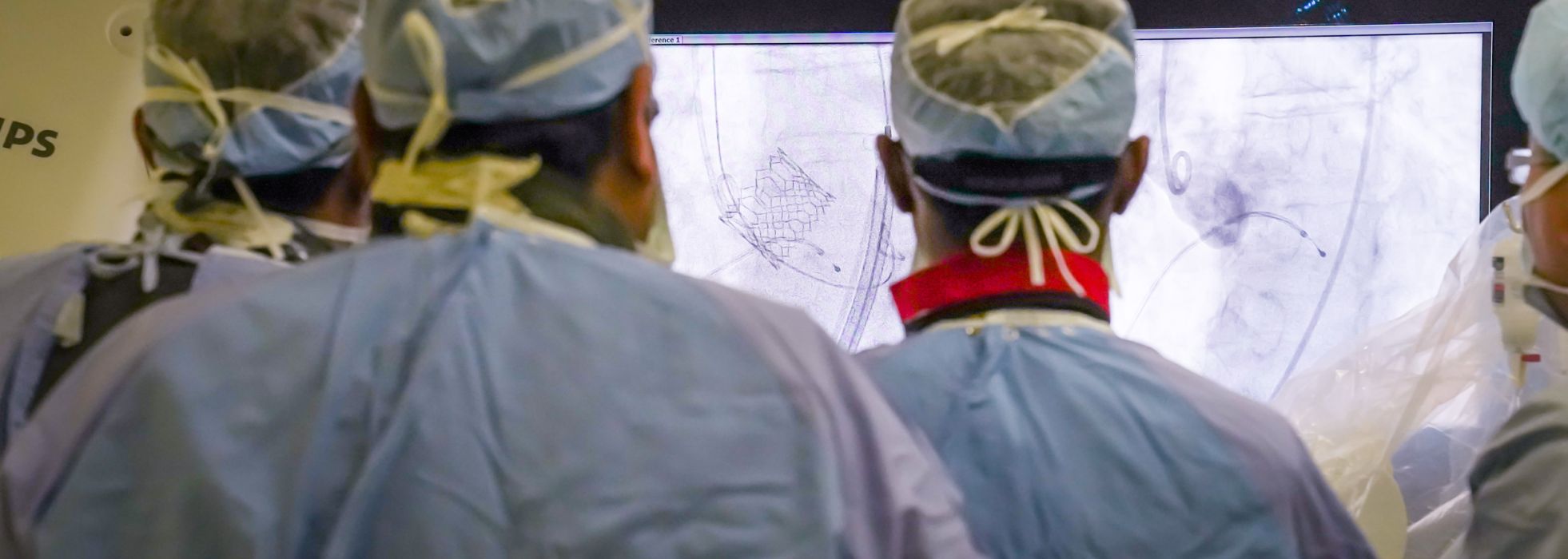 Interventional cardiologists looking at screen int the cath lab