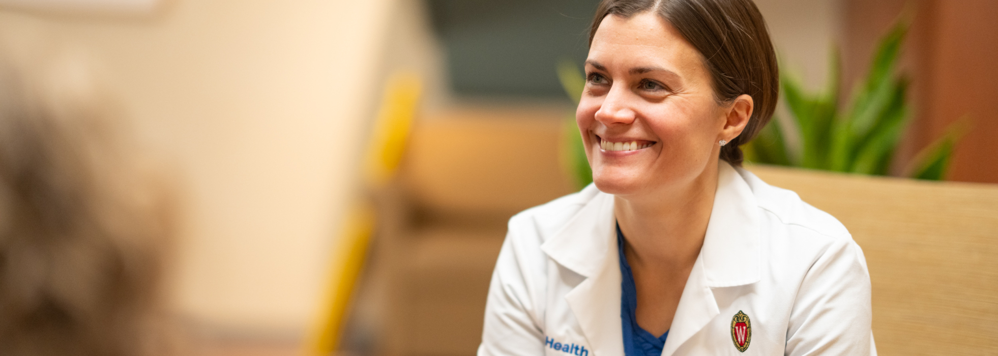 Dr. Jackie Kruser seated and smiling while talking to others in a hospital seating area