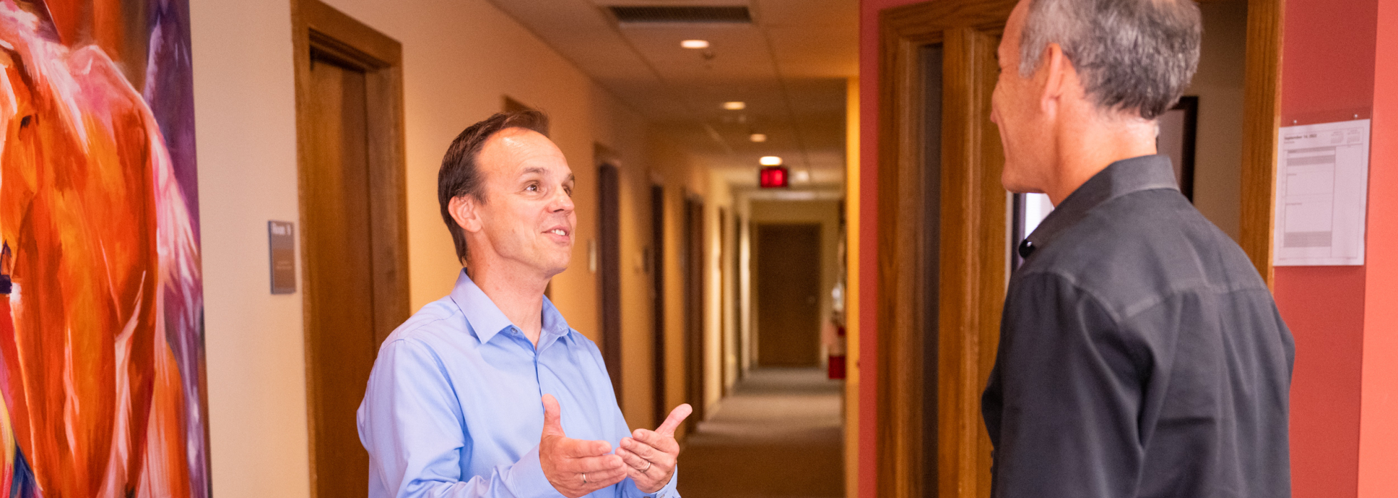 Dr. Mark Micek talking to another doctor in a hallway.