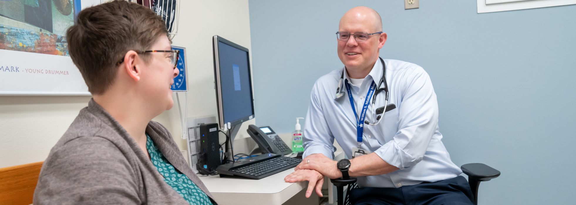 Dr. Christopher Crnich sits at a clinic desk talking with a colleague 