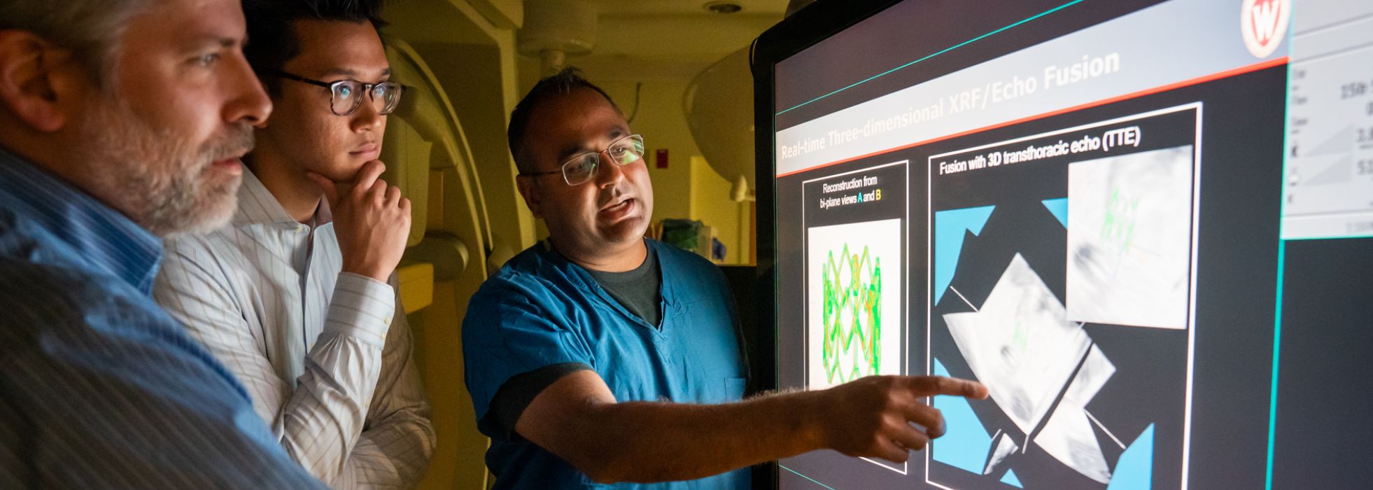 photo of Dr. Amish Raval, student and collaborator looking at image in the cath lab