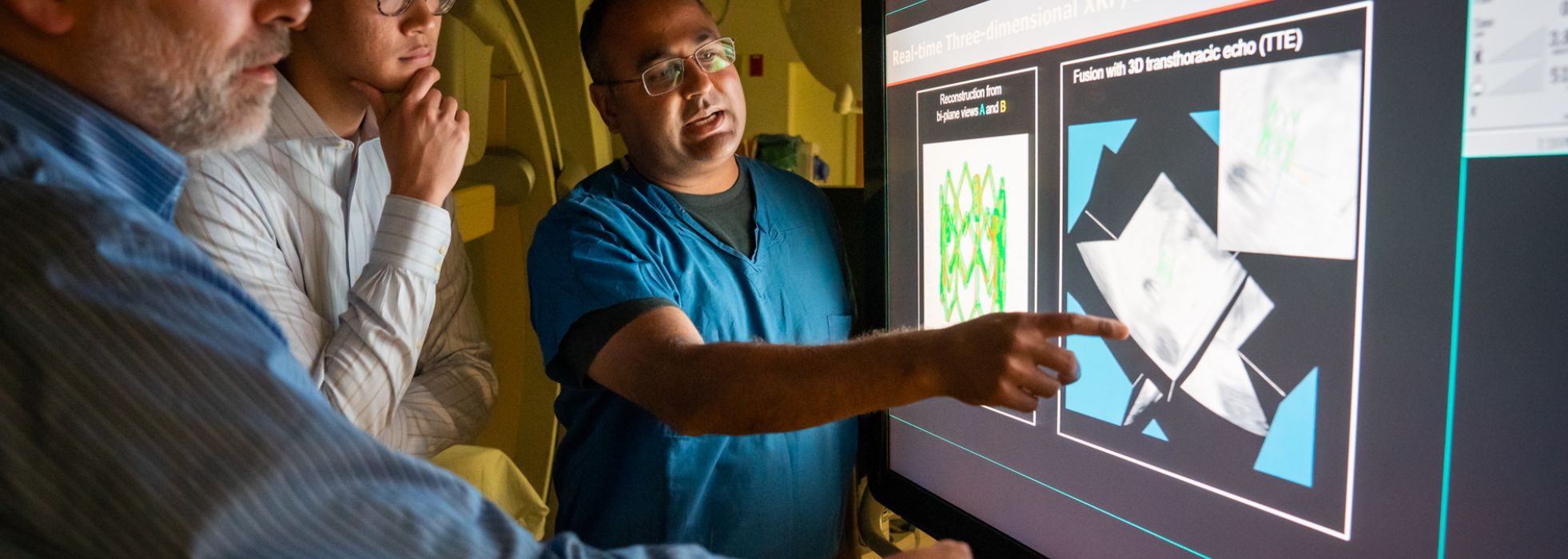 photo of Dr. Amish Raval, student and collaborator looking at image in the cath lab