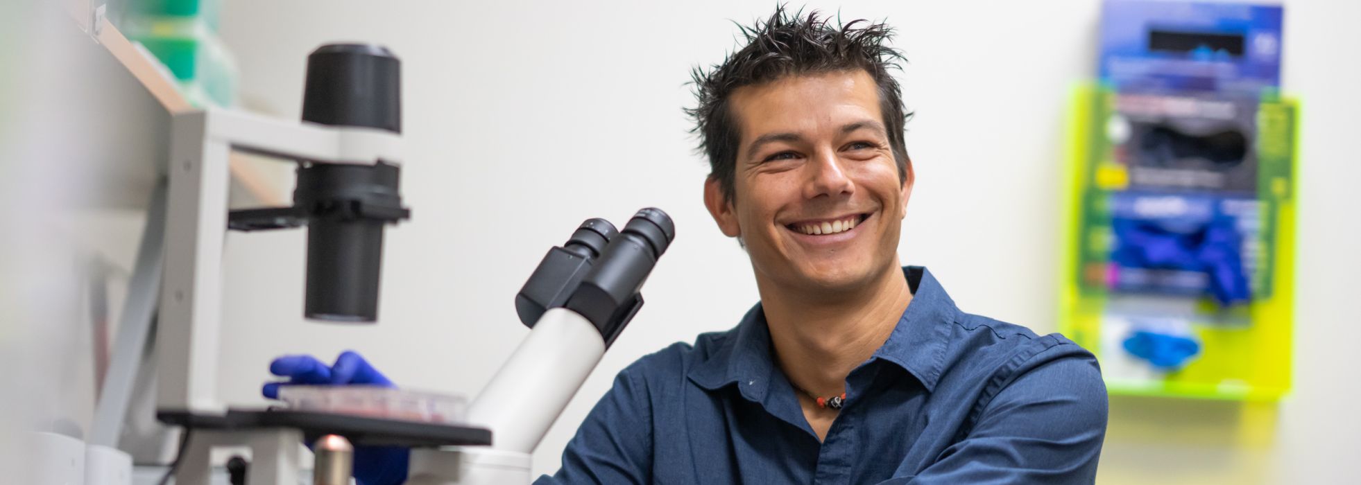 Photo of a smiling Dr. Andrea Galmozzi at a microscope