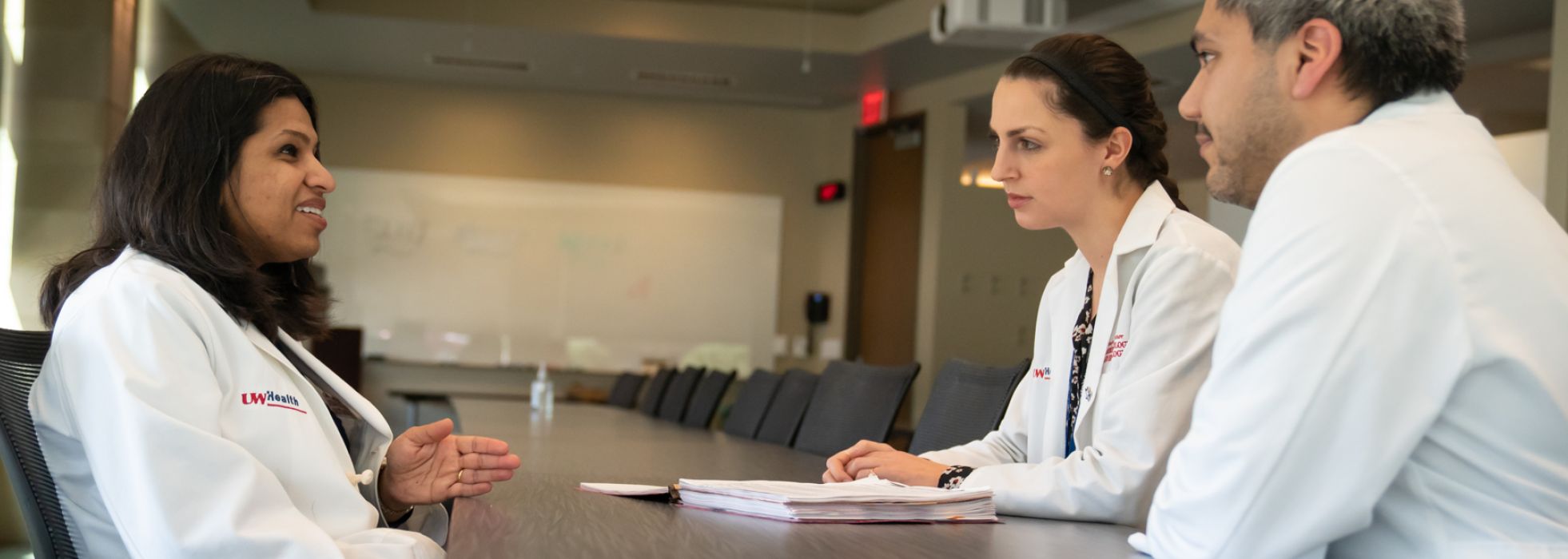 Photo of Dr. Sumona Saha at a table discussing clinical research with others 