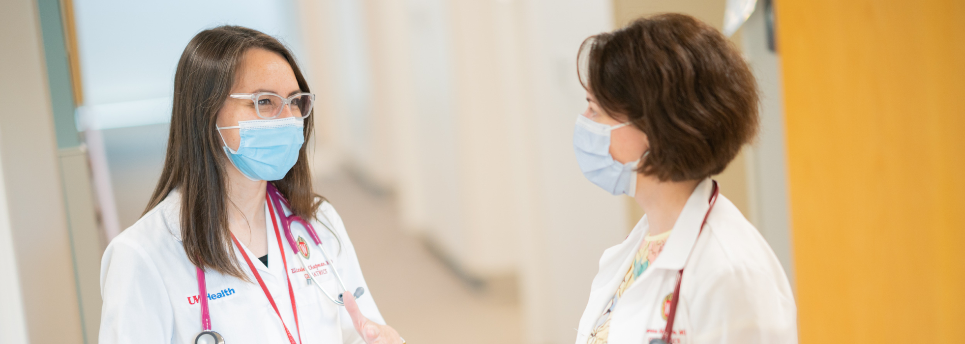 Dr. Elizabeth Chapman wears a white coat and talks with a colleague