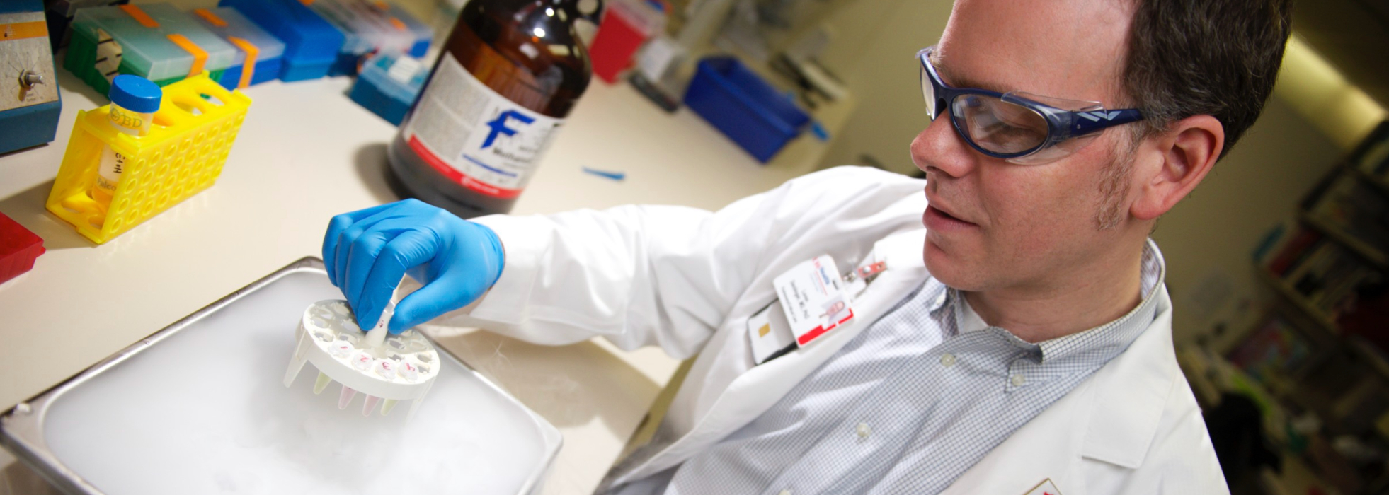 Dr. Loren Denlinger in a white coat working in the lab