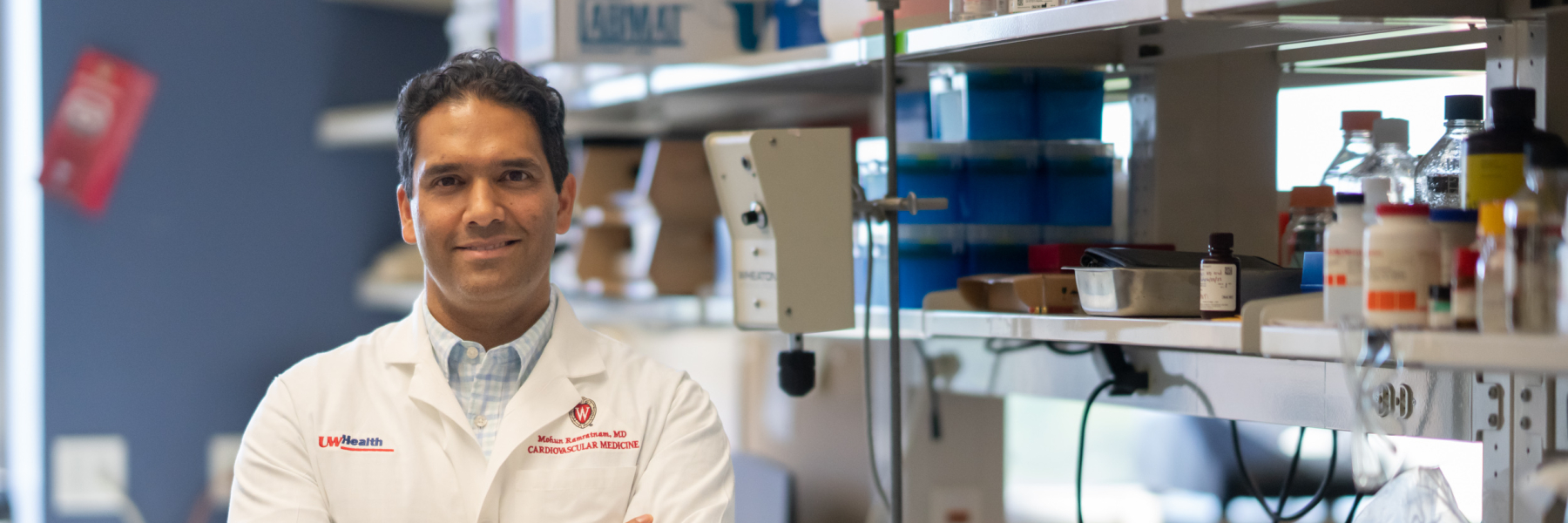 photo of Dr. Mohan Ramratnam wearing white coat and with arms crossed in his lab