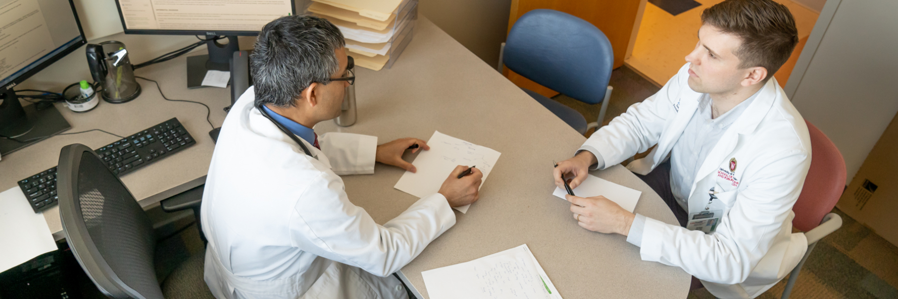 overhead photo of Dr. Dhital and fellow talking in office