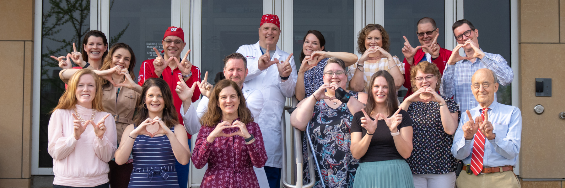 Group photo of congenital heart team making W sign with their hands