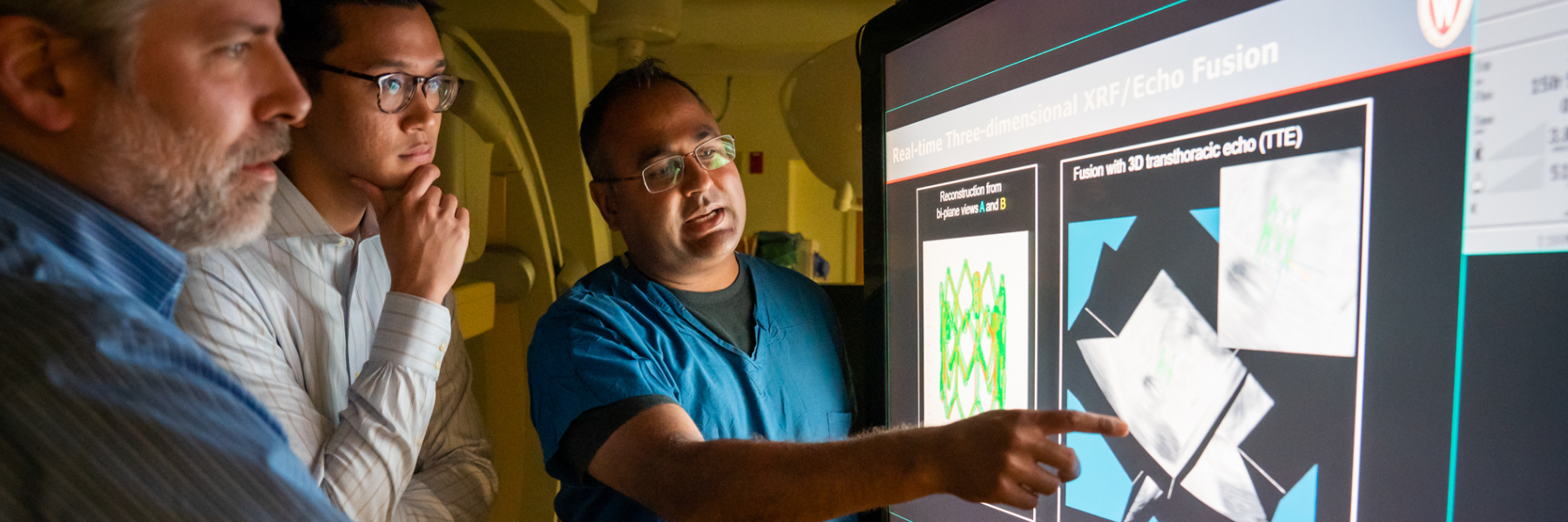 photo of Dr. Amish Raval, student and collaborator looking at image in the cath lab