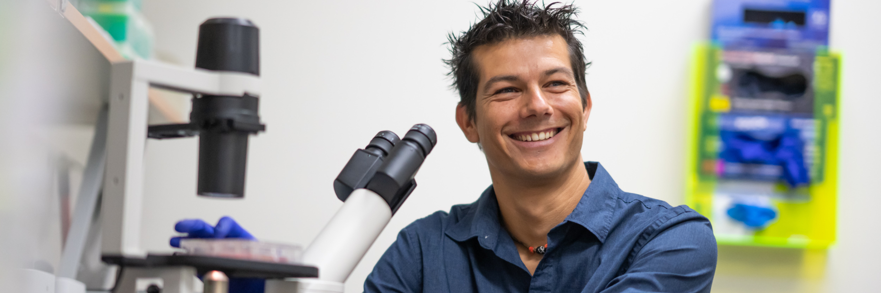photo of Dr. Andrea Galmozzi smiling at a microscope