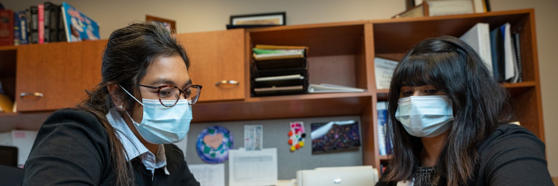 photo of Dr. Anne Marie Singh talking to fellow at desk 