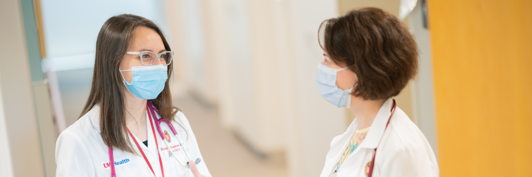 Dr. Elizabeth Chapman wears a white coat and talks with a colleague