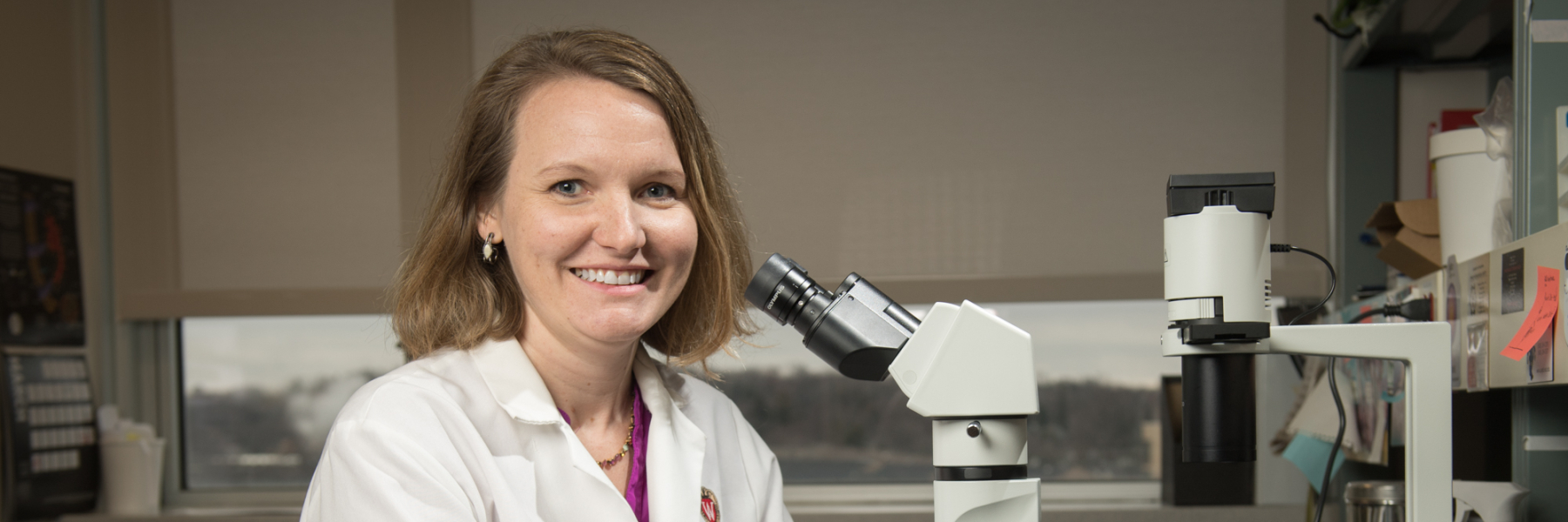 Dr. Dawn Davis in white coat with microscope in lab