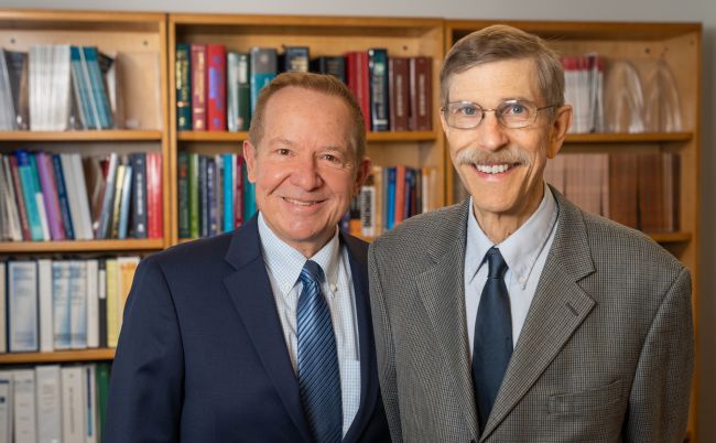 Drs. Michael Fiore and Timothy Baker stand in front of book shelves