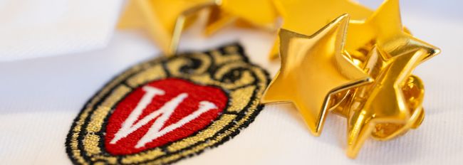 Star pins on a white doctor's coat with the UW crest