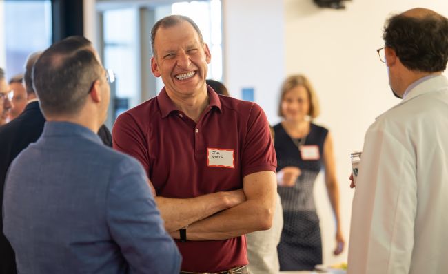 Dr. Stein laughing while wearing a red polo shirt.