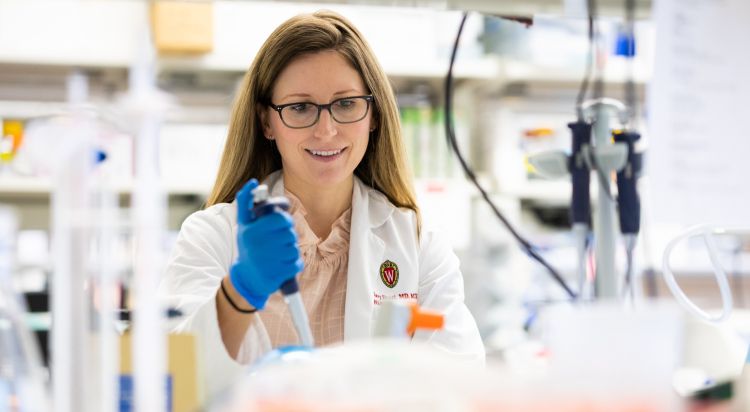 photo of Dr. Hilary Faust holding a pipette in her lab