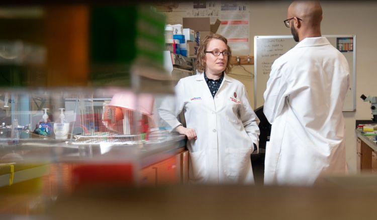 photo of Dr. Sarah Panzer talking to colleague in the lab