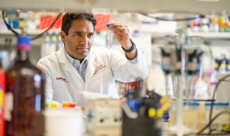 photo of Dr. Mohan Ramratnan in white coat working at bench