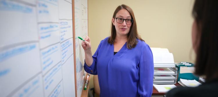 photo of Dr. Jen Weiss talking at a whiteboard with a colleague
