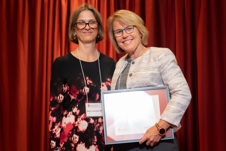 Dr. Betsy Trowbridge and Dr. Ann Schmidt in front of red curtain at a Department of Medicine awards ceremony