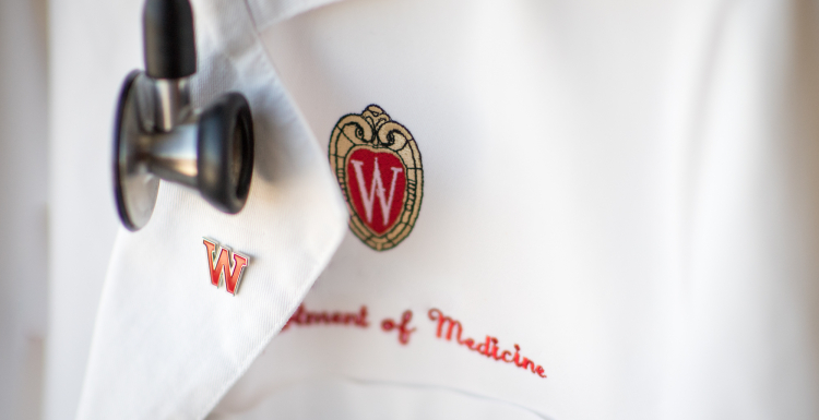 A white lab coat with Department of Medicine stitched in red under the UW–Madison crest.