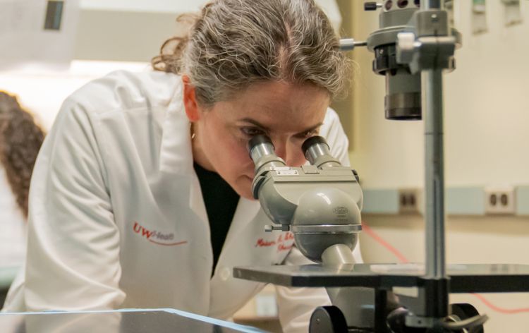 Miriam Shelef, MD, PhD, associate professor, Rheumatology, examines slides under a microscope.