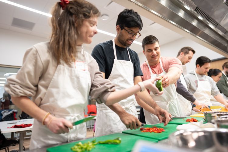 Photo of PG-1s Kara Donovan, MD; Yasgh Hegde, MD; and Tyler Rubeor, MD, trying their hand at vegetable preparation in the Bakke Recreation Center.