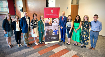 Department of Medicine faculty posing next to a Department of Medicine banner.