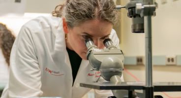 Miriam Shelef, MD, PhD, associate professor, Rheumatology, examines slides under a microscope.
