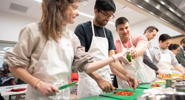 Photo of PG-1s Kara Donovan, MD; Yasgh Hegde, MD; and Tyler Rubeor, MD, trying their hand at vegetable preparation in the Bakke Recreation Center.