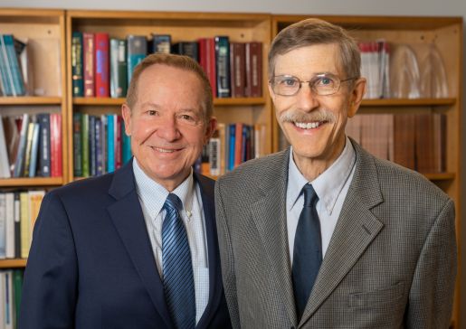 Drs. Michael Fiore and Timothy Baker stand in front of book shelves