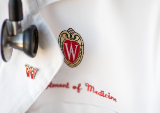Physician's white coat embroidered with UW logo and the words Department of Medicine, with a W red enamel pin and stethoscope.