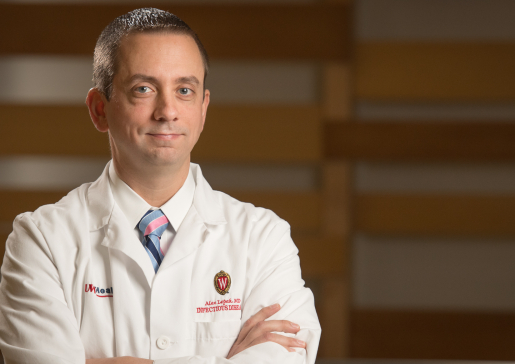 Portrait of Dr. Alex Lepak wearing a white coat with arms folded