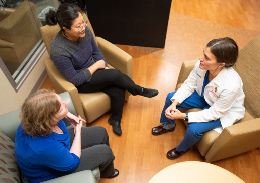 Dr.Jackie Kruser in white lab talking with two colleagues in a seating area of University Hospital