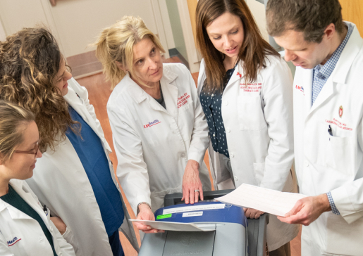 Overhead photo of five cardiologists in white coats in a clinic huddle