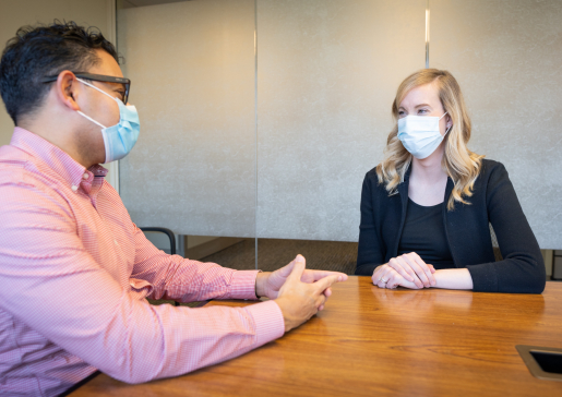 Drs. Freddy Caldera and Megan Lutz talk at a conference room table