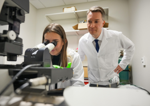 Dr. Alexey Glukhov watches as a research colleague works at a microscope