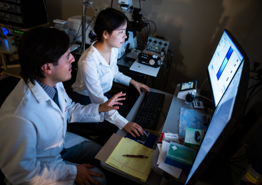 Dr. Francisco Alvarado and member of lab team in front of computer screens in darkened lab