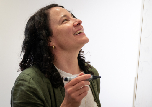 Dr. Caitlin Pepperell smiling and writing on a whiteboard