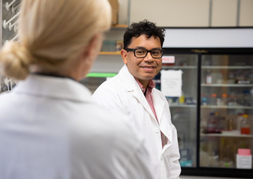 Freddy Caldera smiling back at one of his lab colleagues.